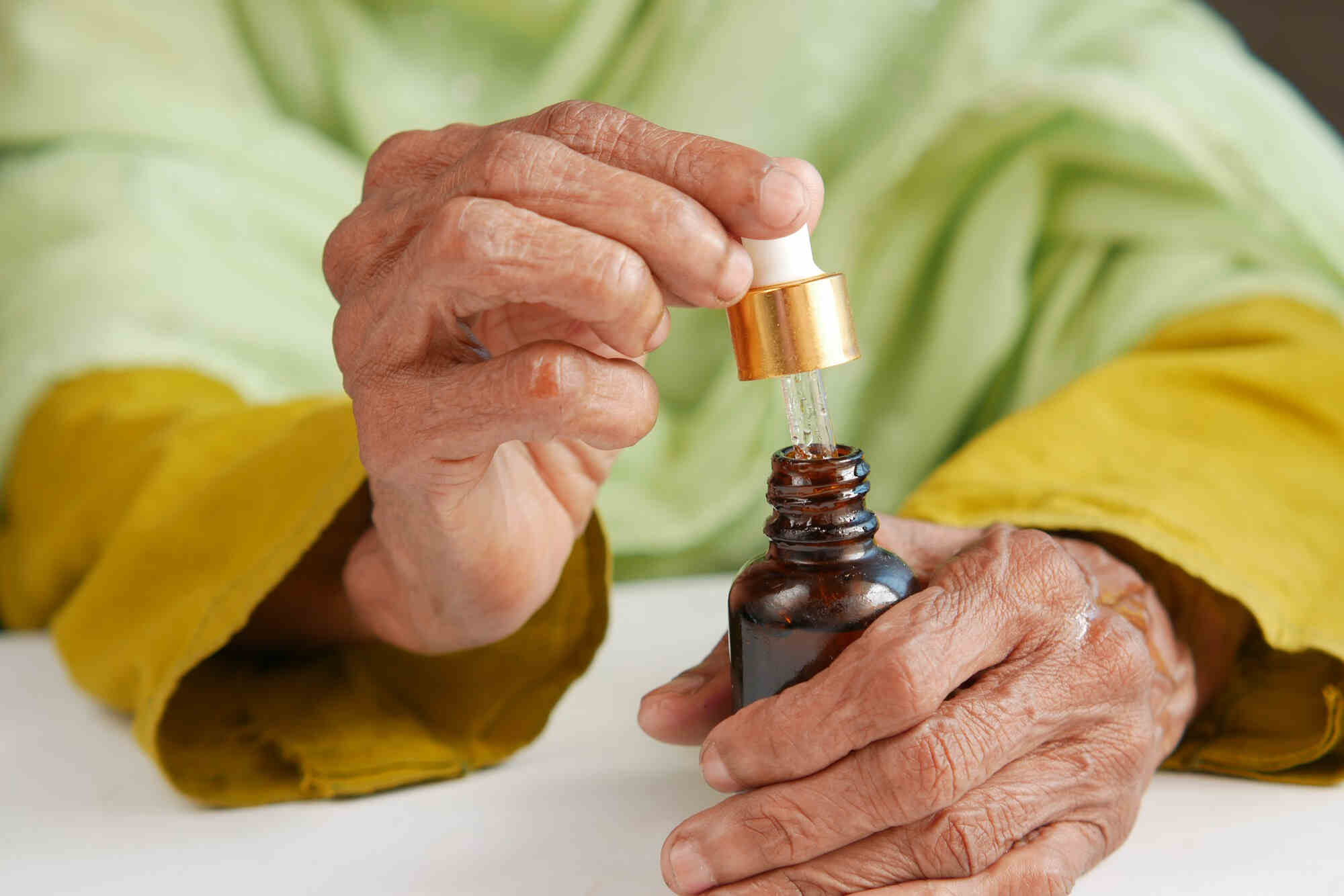 Elderly woman using CBD oil to relieve Parkinson's symptoms