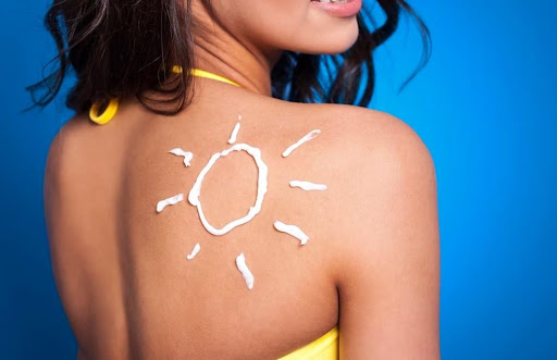 žena s nakresleným slnkom opaľovacím krémom na lopatke